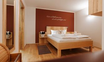 A modern bedroom with a double bed and white bedding. The walls are painted in soft colors, and the room is friendly and inviting.