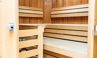 A rustic sauna with wooden paneling and several benches. The room is bright and designed to be inviting.