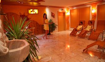 A cozy spa area with relaxing loungers and plants. Two women enjoy the tranquility in soft light.
