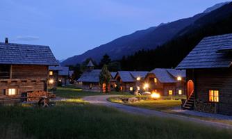 A picturesque village view in the mountains at night. The wooden houses glow gently in the twilight.