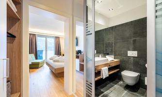 A modern hotel room with an adjoining bathroom. The decor is stylish and brightly designed.