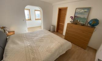 A cozy bedroom with a large bed and a wooden table. A picture hangs on the wall and a globe is on the nightstand.