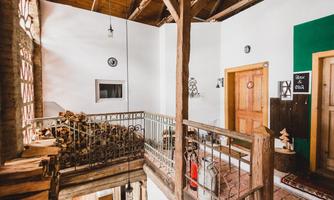 A cozy interior with wooden details and an open balcony. On the left side, logs are stacked, while the walls are warmly designed.