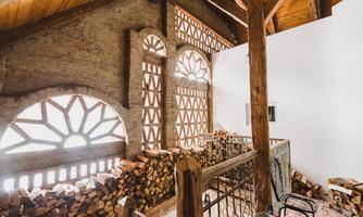 A cozy interior view with wood stacks and large windows. The room design combines rustic elements with a modern style.