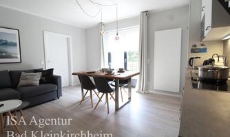 A modern living room with a gray sofa and a wooden table. Large windows provide plenty of daylight and a bright atmosphere.