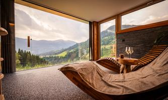 A cozy room with a view of the mountains. A chaise lounge and two glasses are ready to enjoy the scenery.