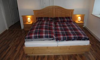 A cozy bedroom with a double bed and checkered bedspreads. The furniture is made of wood, and there is soft light from the bedside lamps.