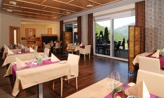 An elegant restaurant with modern tables and chairs. Large windows offer a view of the surrounding nature.