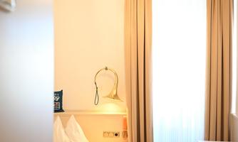 A cozy hotel room with a double bed and a desk. Large windows let in plenty of light.