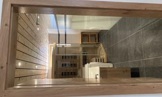 A modern sauna area with wooden paneling and glass walls. The room has bright tiles and offers a relaxing atmosphere.