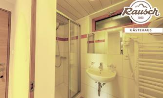 A bright bathroom with a shower, a sink, and a towel warmer. The walls are adorned with friendly white tiles.
