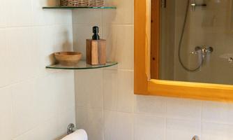 A modern bathroom with a washbasin and mirror. The shelves are decorated with towels and bathroom supplies.