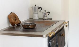 A modern kitchen with a cooktop and a coffee pot. On the counter, there’s a baking dish and a decorative fish design.