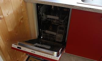 An open dishwasher in a kitchen. It shows clean dishes and a modern design.