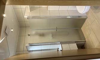 A modern bathroom with a shower cubicle and a toilet. The walls are tiled and the decor is bright and friendly.