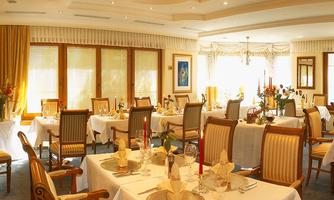 An elegant restaurant with nicely set tables. The light streams gently through the windows, creating a cozy atmosphere.
