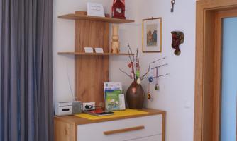 A cozy entrance area with a wooden cabinet and a decorative vase. On the shelf are various items, including a small sculpture and an ornate branch.