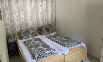 A simple room with two single beds and a plain wood design. The walls are painted in a neutral color.