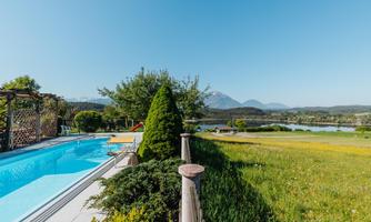 A beautiful outdoor area with a pool and a green lawn. In the background, mountains and a clear sky are visible.