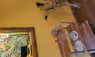 A colorful room with yellow walls and a large mirror. On a shelf, there are decorative objects and a vase with feathers.