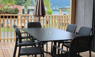 A cozy terrace area with a table and chairs. In the background, plants and a beautiful landscape are visible.