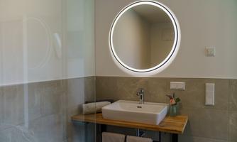 A modern bathroom with a stylish sink and a round mirror. The walls are in neutral colors and the wooden surface adds a warm atmosphere.