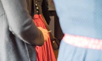 A person in traditional clothing stands nearby. The colors of the garments are red and blue, with striking details.
