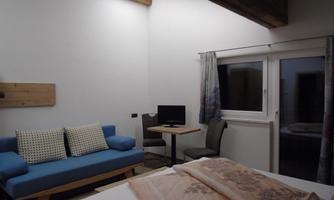 A modern room with a comfortable sofa and a table. Large windows provide plenty of daylight.
