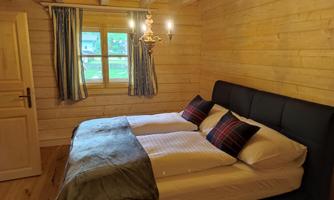 A cozy bedroom with a large bed and wooden panels. Soft bedding and a window create an inviting atmosphere.