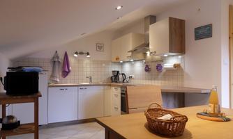 A modern kitchen with bright cabinets and countertops. On the table, there is a basket and a drink.