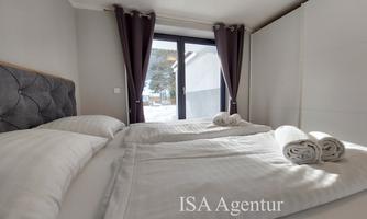A cozy bedroom with two beds and fresh towels. Large French doors let in plenty of light.