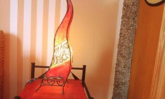 A decorative table lamp with a curved shape and red glass panes. It stands on a black table with a red tablecloth.