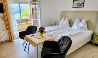 A cozy bedroom with a large bed and two comfortable chairs. Large windows offer a nice view outside.