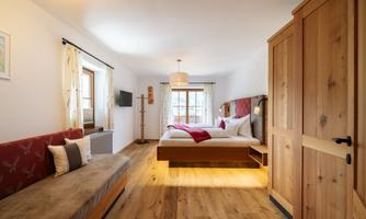 A cozy bedroom with wooden furniture and a large bed. The room has plenty of daylight and an inviting atmosphere.