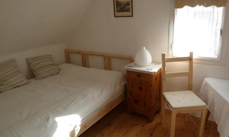 A simple bedroom with a bed, a table, and a chair. The room has a window that lets in natural light.