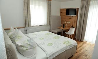 A modern hotel room with a large bed and a desk. The bright curtains let in plenty of light and create an inviting atmosphere.