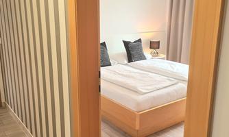 An elegant bedroom with a large bed and stylish cushions. The soft lighting creates a cozy atmosphere.
