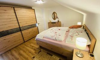 A cozy bedroom with a large double bed and beautiful bedding. The room is decorated with wooden cabinets and warm lighting.