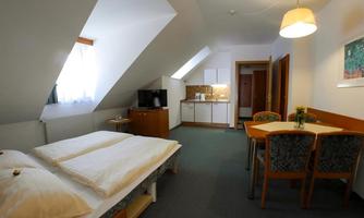 A cozy room with a double bed and a small dining area. The kitchen is integrated in a corner, and the room has a bright atmosphere.