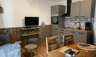 A modern kitchen with a cozy living area. The interior is simple and stylish with wooden furniture and an interesting wall tile.