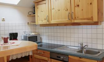 A cozy little kitchen with wooden cabinets and a countertop. It is brightly lit by a skylight.