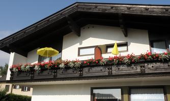 A picturesque house with a balcony full of flowers. Two yellow umbrellas add an inviting atmosphere to the scene.
