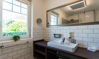 A modern bathroom with an elegant sink and a large mirror. The room has plenty of natural light and a tranquil atmosphere.
