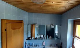 A bathroom with two sinks and a wooden ceiling. There is a mirror and some toiletries on the sink.