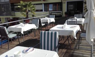 A terrace with covered tables and chairs. The atmosphere is inviting and relaxing, perfect for dining outdoors.