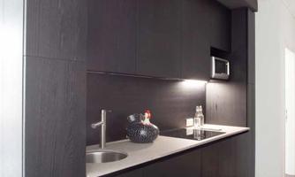 A modern kitchen with dark wood cabinets and a bright work area. The amenities include a sink and a microwave.