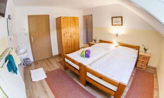 A cozy room with two single beds and wooden furniture. The decoration is simple and inviting, with a dresser and a wardrobe.