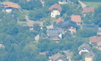 A picturesque residential area with many houses and lush greenery. The sky is clear, and the surroundings appear calm and peaceful.