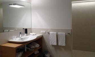 A modern bathroom with a sink, mirror, and towels. The walls are light and the space feels friendly and inviting.