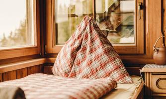 A cozy room with a padded seating area and large windows. The cushions have a red checkered pattern and create an inviting atmosphere.